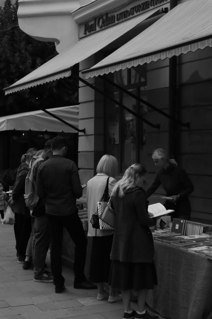 Black and white photo of a lively book market in Chernivtsi, Ukraine, showcasing people browsing outdoor stalls.